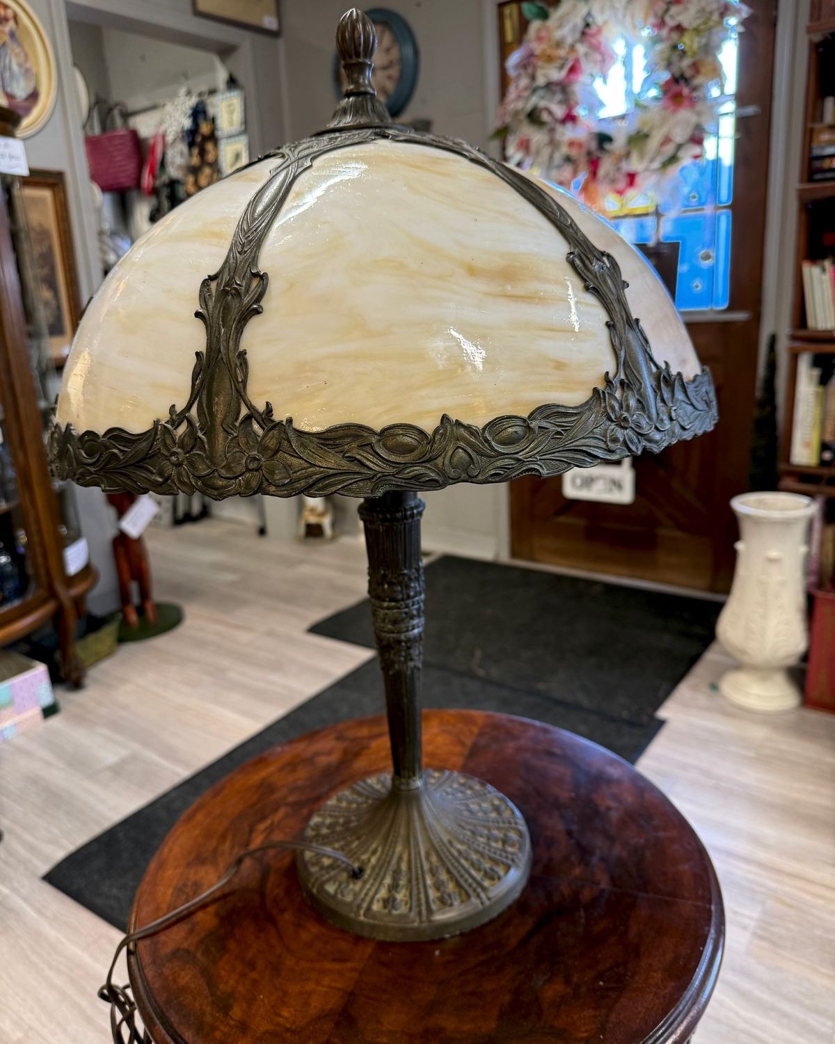 Antique slag glass table lamp with cream and caramel domed shade, ornate brass filigree overlay, and fluted brass column base