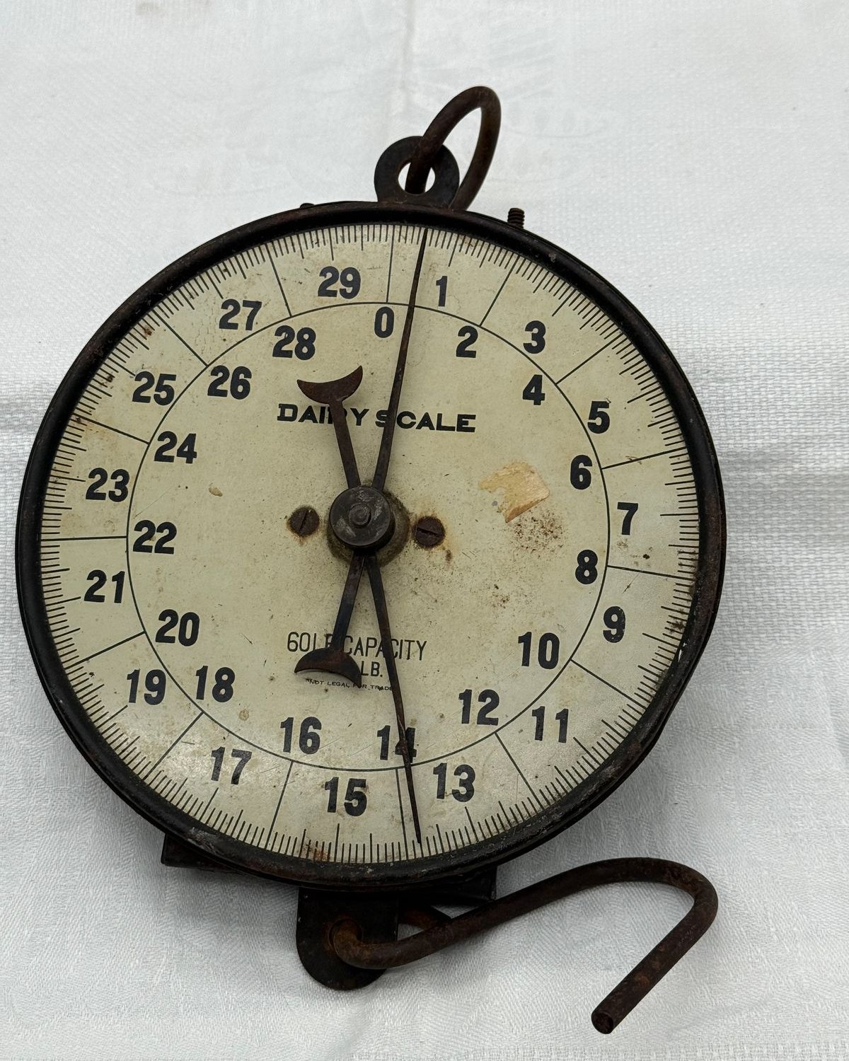 Vintage hanging dairy scale with a round numbered dial reading 60 lb capacity, a hanging ring at top and a weighing hook below.