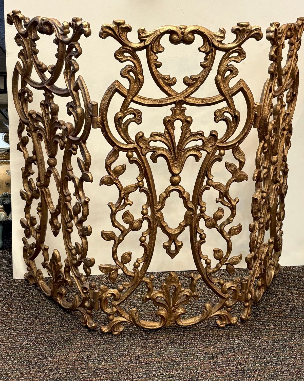 Three-panel gilded cast iron fireplace screen with pierced rococo scrollwork, central cartouches, and acanthus leaf detailing.
