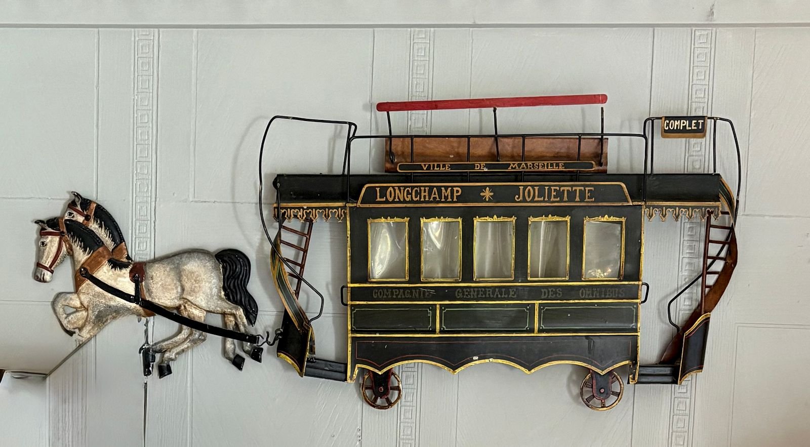 Hand-painted tinplate wall sculpture of a horse-drawn double-decker omnibus lettered Longchamp Joliette and Compagnie Generale des Omnibus, with a dappled gray horse.